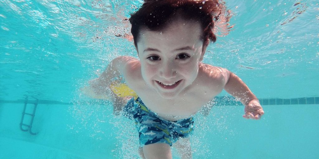 photo of child enjoy swimming in a pool with treated water